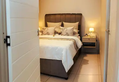 a bed with a wooden headboard in a bedroom at Mbombela Sunrise Retreat in Boschrand