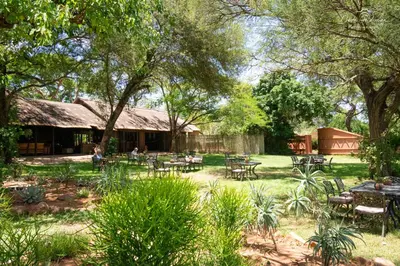 a garden with tables and chairs in front of a building at Mohlabetsi Safari Lodge in Hoedspruit