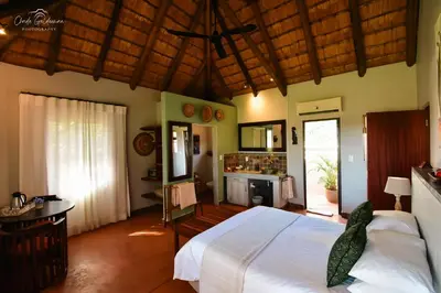 a bedroom with a large white bed and a kitchen at Mohlabetsi Safari Lodge in Hoedspruit