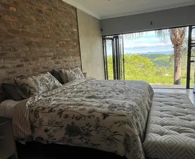a bedroom with a bed and a brick wall at Hooggelegen Estate in White River