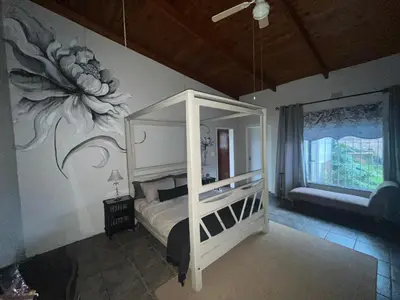 a bedroom with a bed with a flower painted on the wall at Hooggelegen Estate in White River