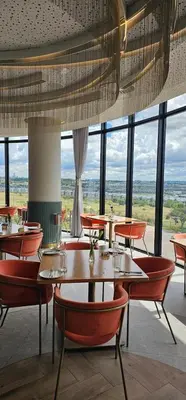 a restaurant with tables and chairs and large windows at Stormside at Ellipse in Midrand