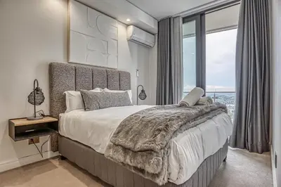 a bedroom with a large bed with a large window at Stormside at Ellipse in Midrand