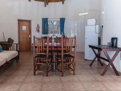 a kitchen with a table and chairs and a refrigerator at Awelani Eco Tourism Lodge in Masisi