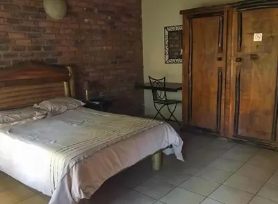 a bedroom with a bed and a brick wall at Lapa Lê Lê Lodge in Ellisras