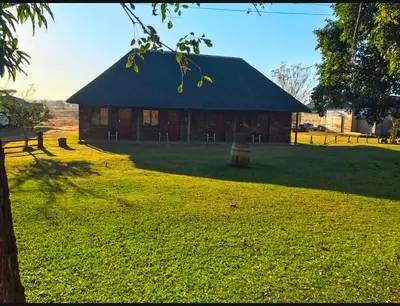 a barn with a black roof on a grass field at Lapa Lê Lê Lodge in Ellisras