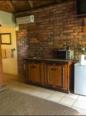 a kitchen with a sink and a brick wall at Lapa Lê Lê Lodge in Ellisras