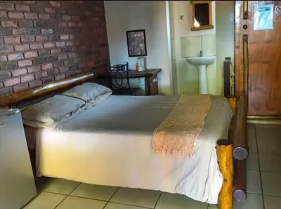 a large bed in a room with a brick wall at Lapa Lê Lê Lodge in Ellisras
