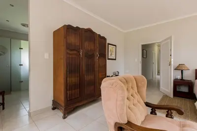 a living room with a chair and a large wooden cabinet at Hacienda Destri Lodge in Wolwefontein