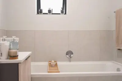 a bathroom with a bath tub with a sink at Work, Travel, Relax in Pure Class in Midrand