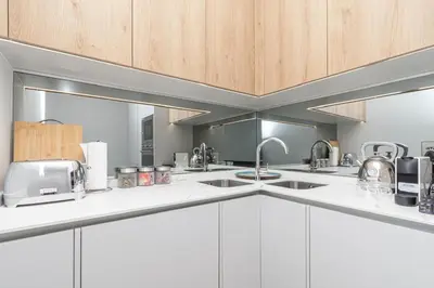 a kitchen with white counters and wooden cabinets at Ellipse Manscave Modern Luxury Apartment in Midrand
