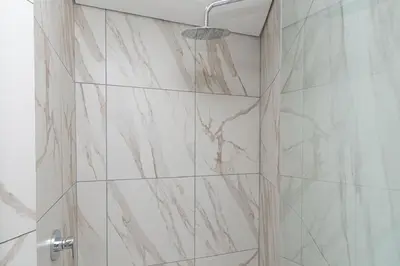 a bathroom with a shower with marble tiles at Ellipse Manscave Modern Luxury Apartment in Midrand
