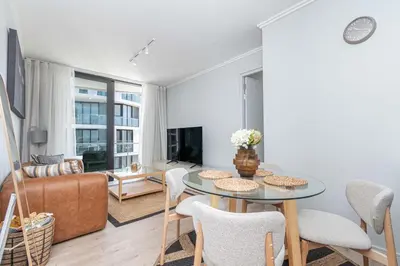a living room with a table and chairs and a couch at Ellipse Manscave Modern Luxury Apartment in Midrand