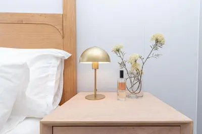 a table with a lamp and a vase with flowers on it at Ellipse Manscave Modern Luxury Apartment in Midrand