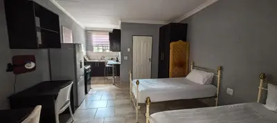 a small room with two beds and a kitchen at BlueHill Residence in White River