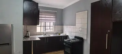 a kitchen with black cabinets and a sink and a stove at BlueHill Residence in White River