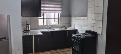 a kitchen with black cabinets and a sink and a stove at BlueHill Residence in White River