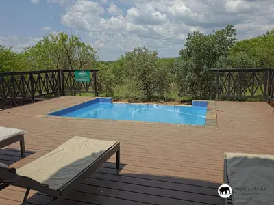 a swimming pool on a wooden deck with two chairs at Mufasa's Den Zebula in Warmbaths