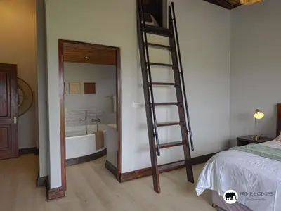 a bedroom with a ladder next to a bath tub at Mufasa's Den Zebula in Warmbaths