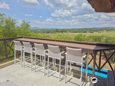 a deck with a wooden table and white chairs at Mufasa's Den Zebula in Warmbaths