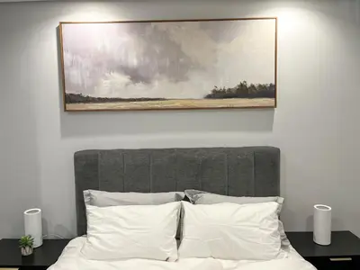a painting hangs above a bed with white pillows at 4208 on Ellipse, Waterfall, Midrand in Midrand