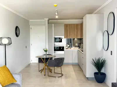 a living room with a table and a kitchen at 4208 on Ellipse, Waterfall, Midrand in Midrand