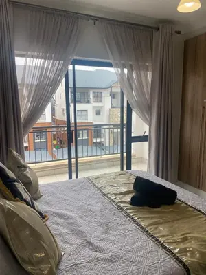 a bedroom with a large bed with a large window at IRIS at THE BLYDE in Pretoria