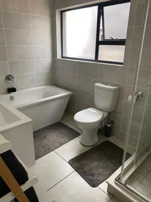 a bathroom with a tub and a toilet and a window at IRIS at THE BLYDE in Pretoria