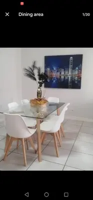 a dining room with a glass table and white chairs at IRIS at THE BLYDE in Pretoria