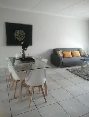 a living room with a glass table and white chairs at IRIS at THE BLYDE in Pretoria