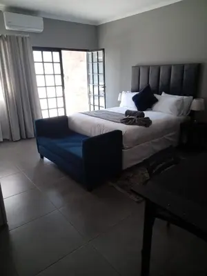 a bedroom with a large bed and a blue couch at DHALI COUNTRY house in Ermelo