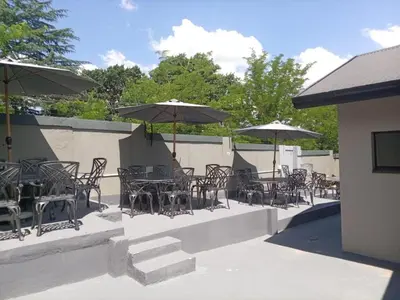 an outdoor patio with tables and chairs with umbrellas at DHALI COUNTRY house in Ermelo