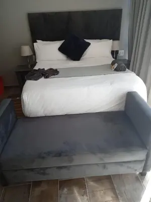 a large bed with a bench in a bedroom at DHALI COUNTRY house in Ermelo