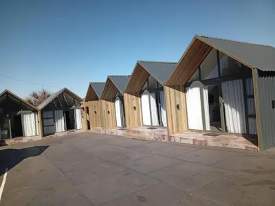 a row of wooden houses in a parking lot at DHALI COUNTRY house in Ermelo
