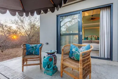 two chairs and a vase sitting on a patio at Bushveld Villa w Pool, Firepit & Outdoor Living in Hoedspruit