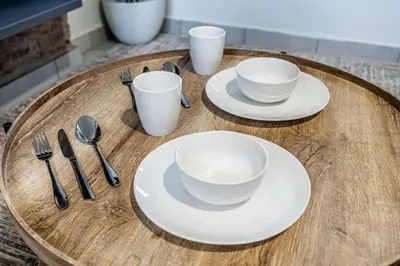 a wooden table with two white plates and silverware at Menlo Park Luxury Free Parking King bed Workstation 3 km to Menlyn Maine in Pretoria