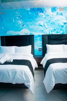 two beds in a room with a painting on the wall at Meriam Base Lodge in Kempton Park