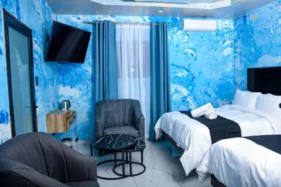 a blue room with two beds and a chair at Meriam Base Lodge in Kempton Park