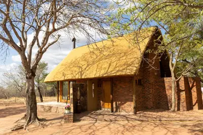 a small brick building with a thatched roof at Tholo Bush Stay