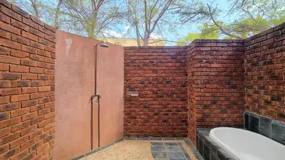 a brick wall with a shower and a bath tub at Tholo Bush Stay