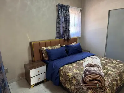 a bedroom with a bed with blue sheets and a window at Binu motel Kempton park in Johannesburg