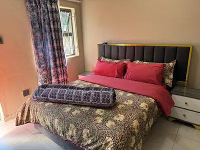 a bedroom with a large bed with red pillows at Binu motel Kempton park in Johannesburg