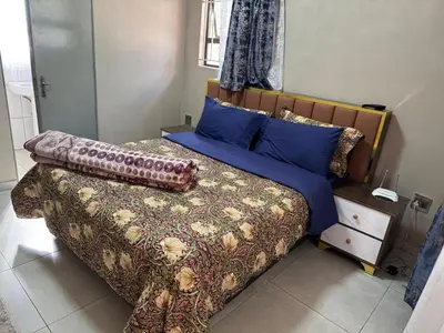 a bedroom with a large bed with blue pillows at Binu motel Kempton park in Johannesburg