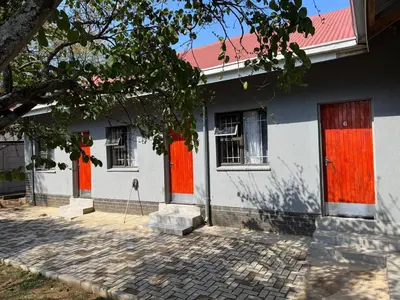 a white house with red doors and a tree at Binu motel Kempton park in Johannesburg