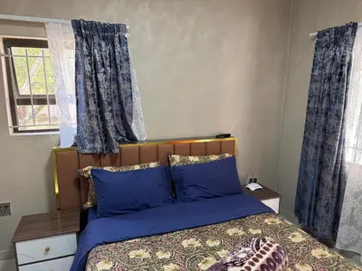 a bedroom with a bed with blue pillows and a window at Binu motel Kempton park in Johannesburg