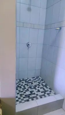 a shower with a black and white checkered floor at Binu motel Kempton park in Johannesburg