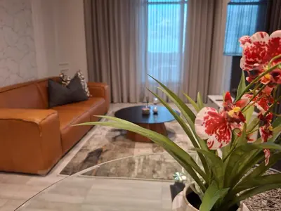a living room with a couch and a glass table with flowers at 139 Menlyn Maine in Pretoria