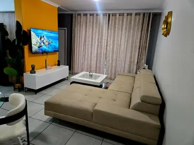 a living room with a couch and a tv at The Blyde Luxury Apartments in Pretoria