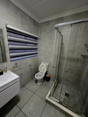 a bathroom with a shower and a toilet and a sink at The Blyde Luxury Apartments in Pretoria