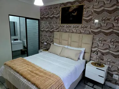 a bedroom with a large bed and a wall at The Blyde Luxury Apartments in Pretoria